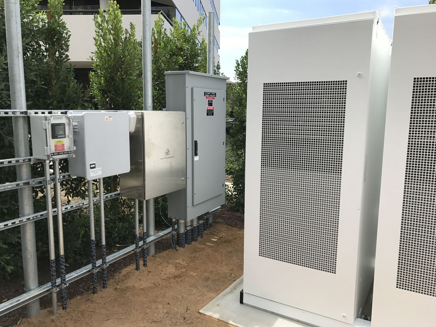 Storage combiner panelboard and metering enclosures on strut beside battery cabinets