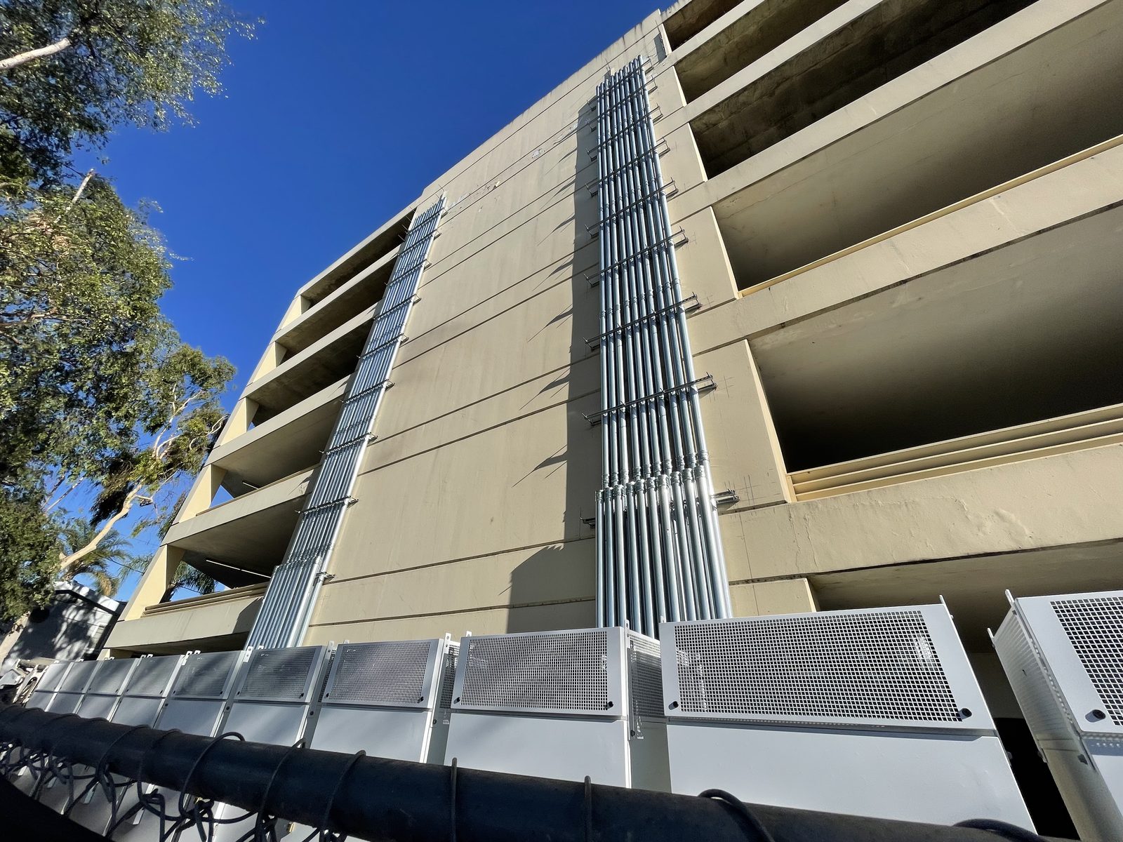 Vertical conduit riser running up the face of a parking structure