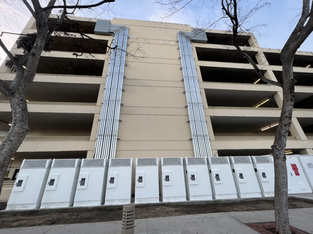 Two conduit riser banks running up a parking structure to a row of twelve power cabinets