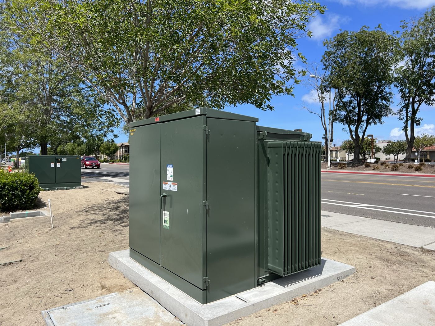 Pad-mount transformer on a new concrete pad beside a public street